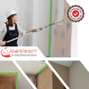 Malerin nutzt eine Farbrolle für präzise Anstriche an einer Wand, gesichert mit grünem Lackiererkreppband. Perfekte Abdeckung und saubere Farbkanten durch zuverlässiges Klebeband. Ideal für professionelle Malerarbeiten.